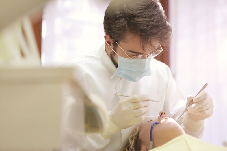 Dentista che indossa mascherina chirurgica per proteggere il paziente da contagi